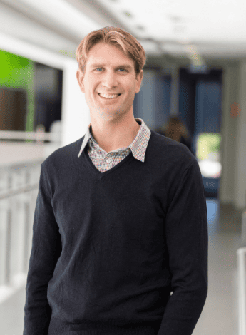 The image is of Dr Aidan Cashin, a researcher of back pain. He is standing outside and wearing a black jumper.